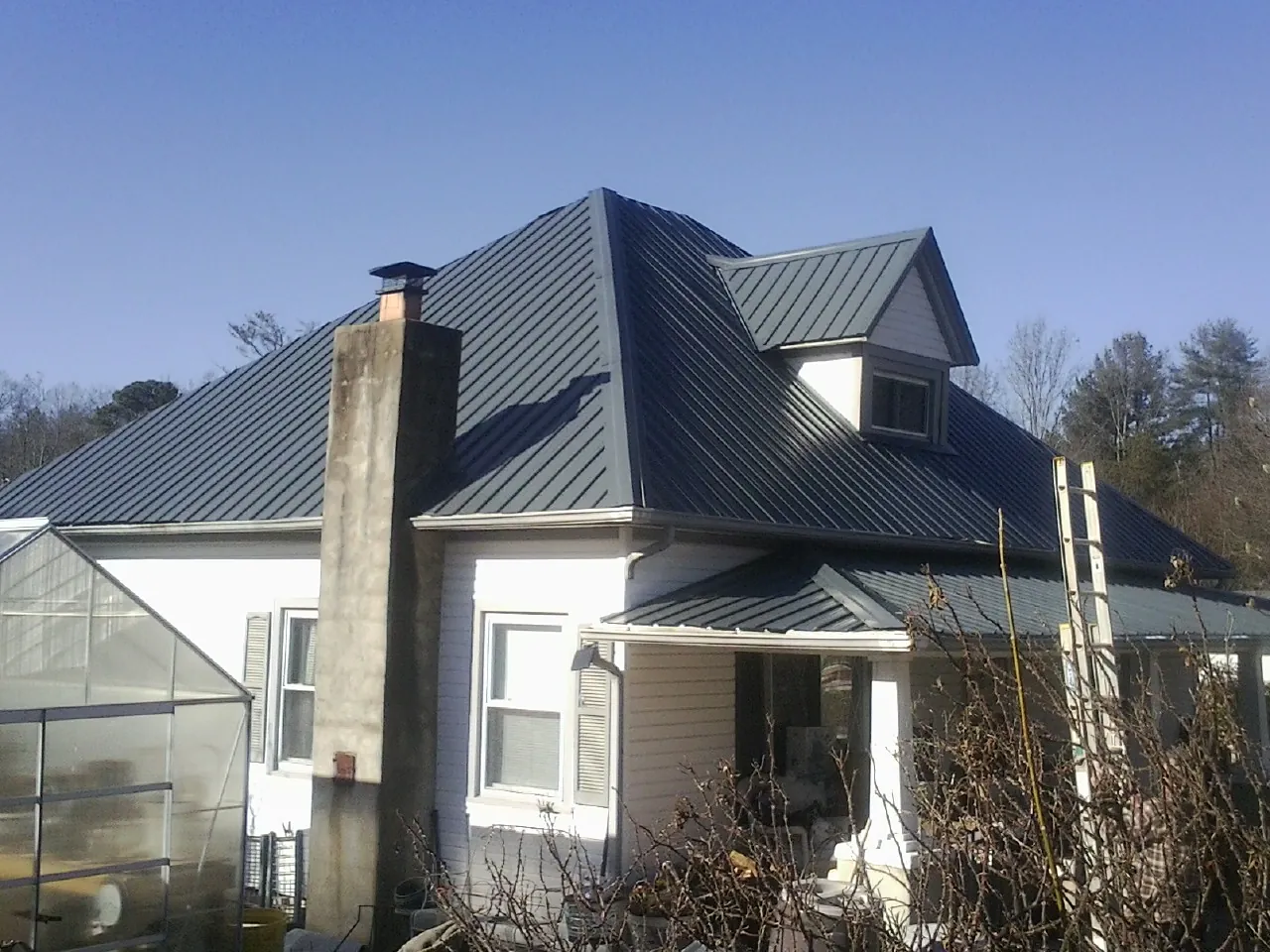 Dark blue standing seam metal roof on a white farmhouse with dormer — Slate & Tile Roof Repair by Roofing Brothers in Mappsville