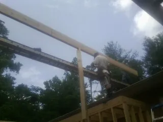 Carpenter setting a ridge beam over a new addition frame — Ice Dam Removal by Roofing Brothers in Mappsville