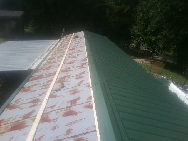 Old rusted panels beside newly installed green metal roofing — Wind Damage Roof Repair by Roofing Brothers in Mappsville
