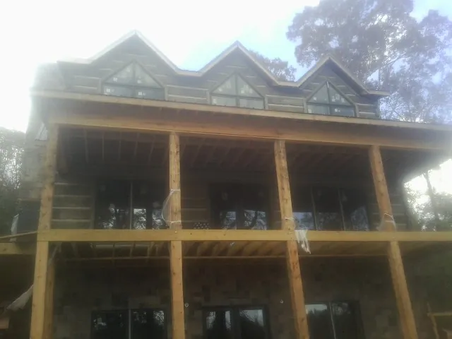 Dormers and porch framing on a large log home under construction — Roof Coating work by our crew in Mappsville