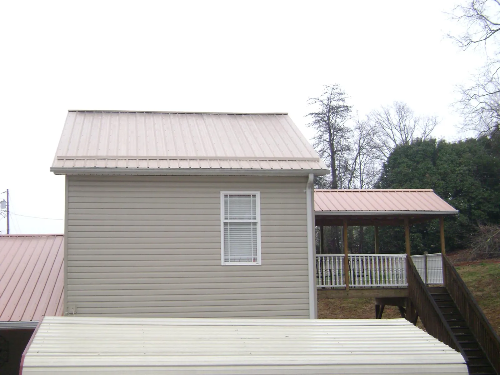 Tan metal roofs on a two story addition and attached porch, from a Roof Replacement job in Mappsville